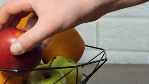 A hand puts fruit into a fruit basket in the kitchen. Fruit basket oranges Stock Footage 194726241