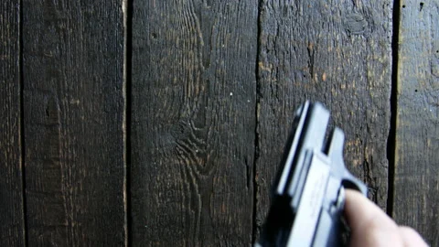 Hand puts a gun on a wooden background Stock Footage 106936641