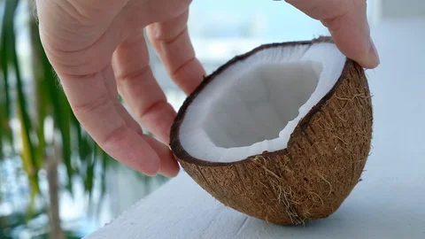 Hand puts half a coconut on a white table Stock Footage 129562364