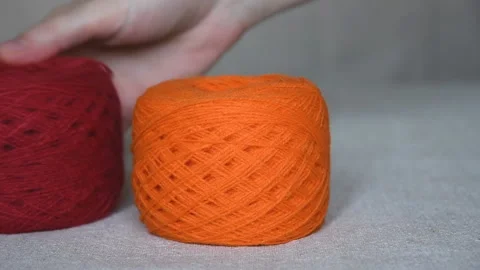 Hand puts multi-colored skeins of woolen yarn and rolls them into the frame Stock Footage 137312569