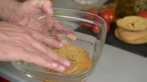 Hand puts one frisa tipical apulian dish in water to moisten before being eaten Stock Footage 156760650
