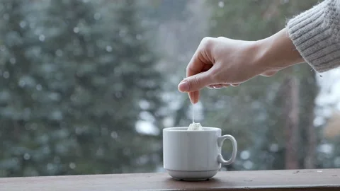 A hand puts a pack of tea into a white cup on a windowsill against a background Stock Footage 150327622