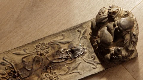 A hand puts a parfumed burning paper in front of a buddha figurine Stock Footage 129759389