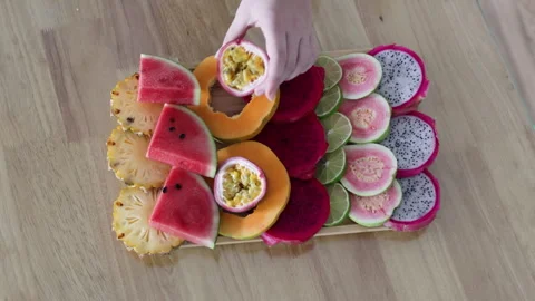 Hand puts passion fruit on plate with tropical fruits. Stock Footage 291767401