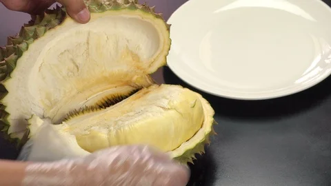 Hand puts peeling durian on white plate Stock Footage