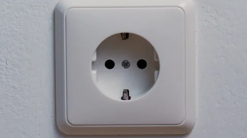 Hand puts a power plug in the wall socket Stock Footage 88387507