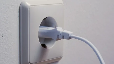 Hand puts a power plug in the wall socket Stock Footage 88387776