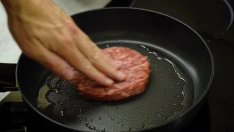 Hand puts raw burger cutlet to fry in frying pan Vidéo 232780515