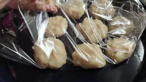 A hand puts raw chicken cutlets in a baking sleeve on a baking sheet 스톡 동영상 311843748