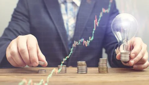 The hand puts a stack of coins with a growing business graph. Panoramic busin Stock Photos