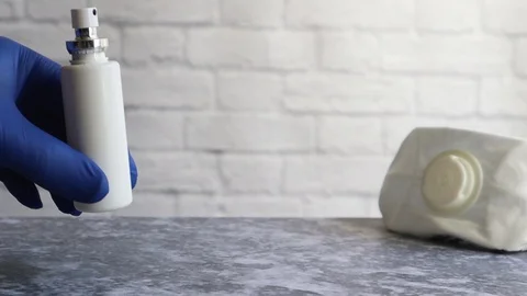 The hand puts on the table an aerosol spray can with an antiseptic with a mask. Stock Footage 127808391