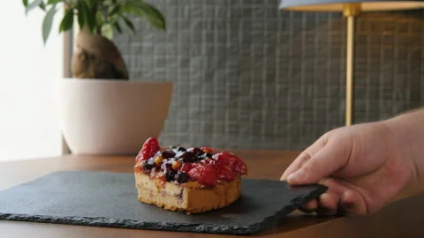 The hand puts on the table a plate with a piece of cheesecake with berries 스톡 동영상 168187083