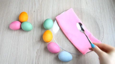 Hand puts a teaspoon next to colored eggs on festive Easter table. Stock Footage 61569536