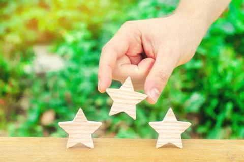 The hand puts the third star on a green background. Quality assessment and po Stock Photos