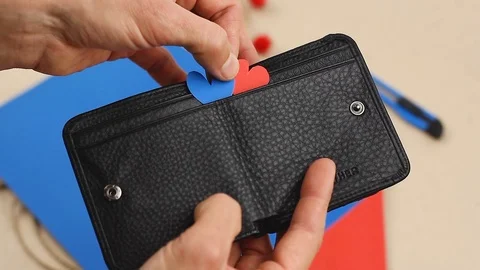 Hand puts two paper hearts red and blue into black leather wallet, valentine Video stock 122419636