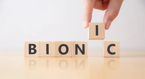Hand puts wooden cubes with BIONIC on table. Stock Photos