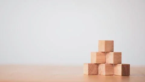 Hand putting and stacking blank wooden cubes on table with copy space Stock Photos