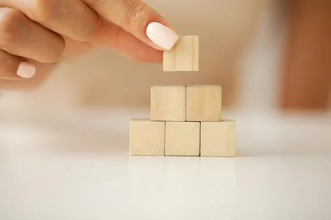 Hand putting and stacking blank wooden cubes on table with copy space for input Stock Photos