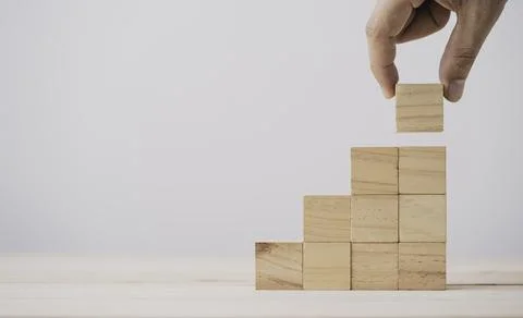 Hand putting and stacking blank wooden cubes on table with copy space Stock Photos