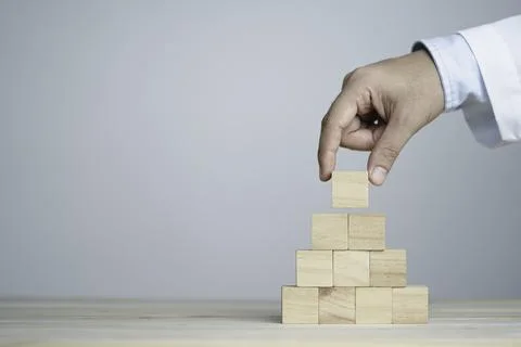 Hand putting and stacking blank wooden cubes on table with copy space Stock Photos