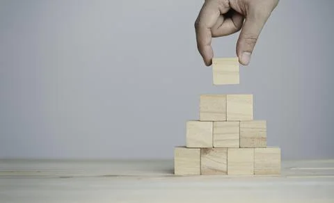 Hand putting and stacking blank wooden cubes on table with copy space Stock Photos