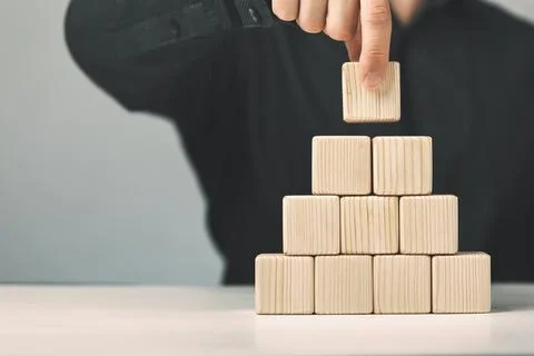 Hand putting and stacking blank wooden cubes on table with copy space for input 库存照片