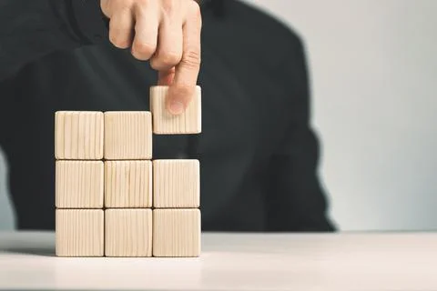 Hand putting and stacking blank wooden cubes on table with copy space for input Stock Photos
