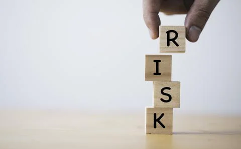 Hand putting and stacking wooden cube block of risk wording for risk manage.. Stock Photos