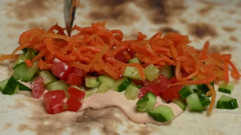 Hand putting carrot on flatbread pita Stock Footage 262214852