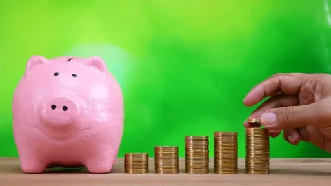 Hand putting coin on stack of golden money coin with pink piggy bank Stock Footage 281139468