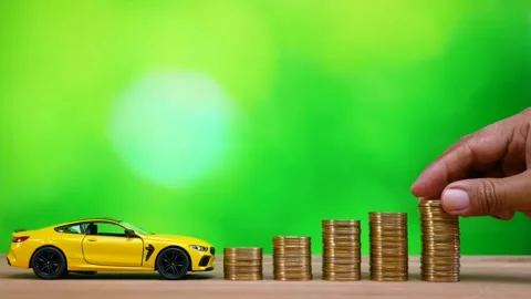 Hand putting coin on stack of golden money coin with miniature car Stock Footage 281139470