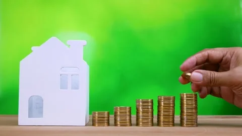 Hand putting coin on stack of golden money coin with miniature house Stock Footage 281139483