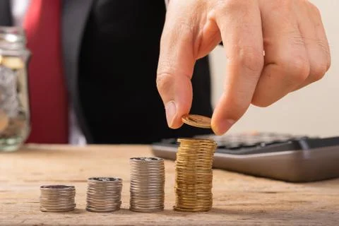 Hand putting coins on stack on table,Saving money concept or Business Growth  Stock Photos