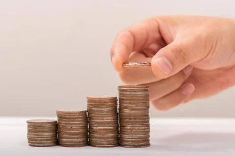 Hand putting coins on stack on table,Saving money concept or Business Growth  Stock Photos