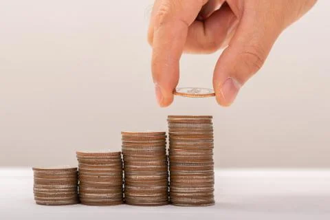 Hand putting coins on stack on table,Saving money concept or Business Growth  Stock Photos