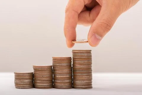 Hand putting coins on stack on table,Saving money concept or Business Growth  Stock Photos