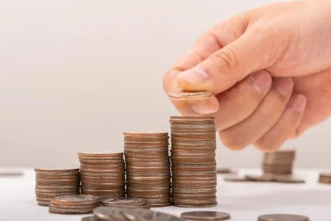 Hand putting coins on stack on table,Saving money concept or Business Growth  Stock Photos