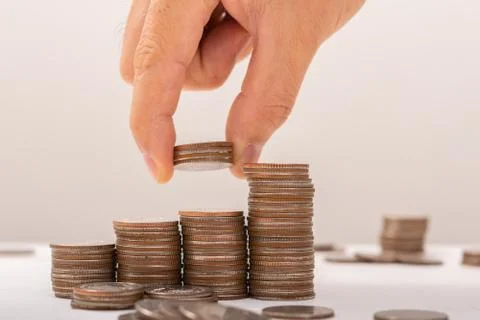 Hand putting coins on stack on table,Saving money concept or Business Growth  Stock Photos