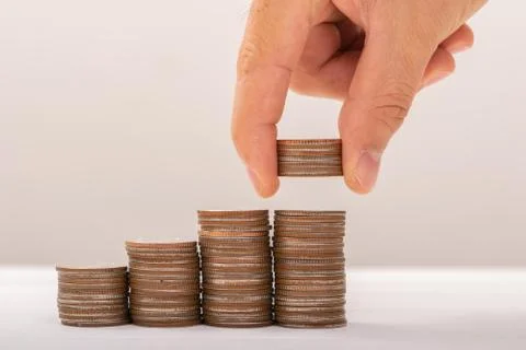 Hand putting coins on stack on table,Saving money concept or Business Growth  Stock Photos
