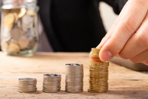Hand putting coins on stack on table,Saving money concept or Business Growth  Stock Photos