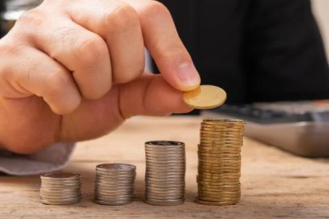 Hand putting coins on stack on table,Saving money concept or Business Growth  Stock Photos
