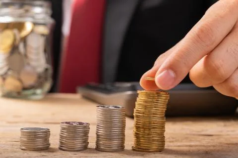 Hand putting coins on stack on table,Saving money concept or Business Growth  Stock Photos