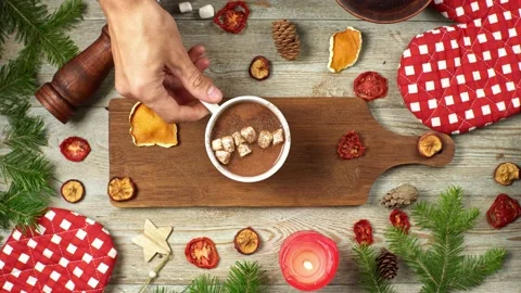 Hand is putting a cup of hot chocolate on a wooden cutting board on a table Stock Footage 196225670