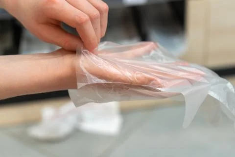 Hand putting on disposable plastic glove for hygienic food handling in bake.. Stock-Fotos