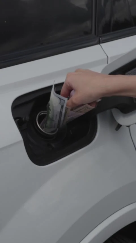 Hand putting dollar banknotes into car fuel tank Stock Footage 339598803