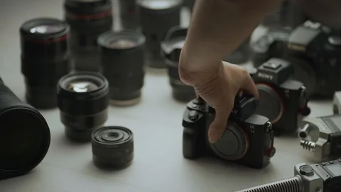 A hand putting down camera between another camera and lens.  Video stock 128406217