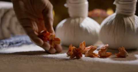 Hand putting down dried flowers on table. Massage sacks filled with herbs set Stock Footage 180628298