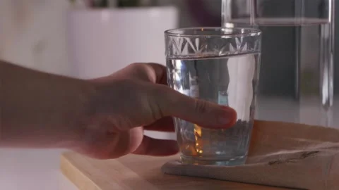 Hand putting down glass of pure water on table in soft morning light 스톡 동영상 344877093
