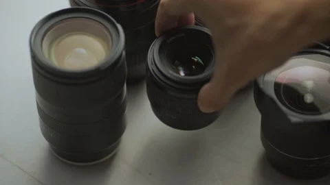 A hand putting down the lens of the camera between another lens. tools of trade  Video stock 128407370