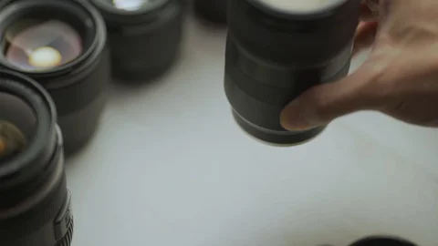 A hand putting down the lens of the camera between another lens. Video stock 128407490